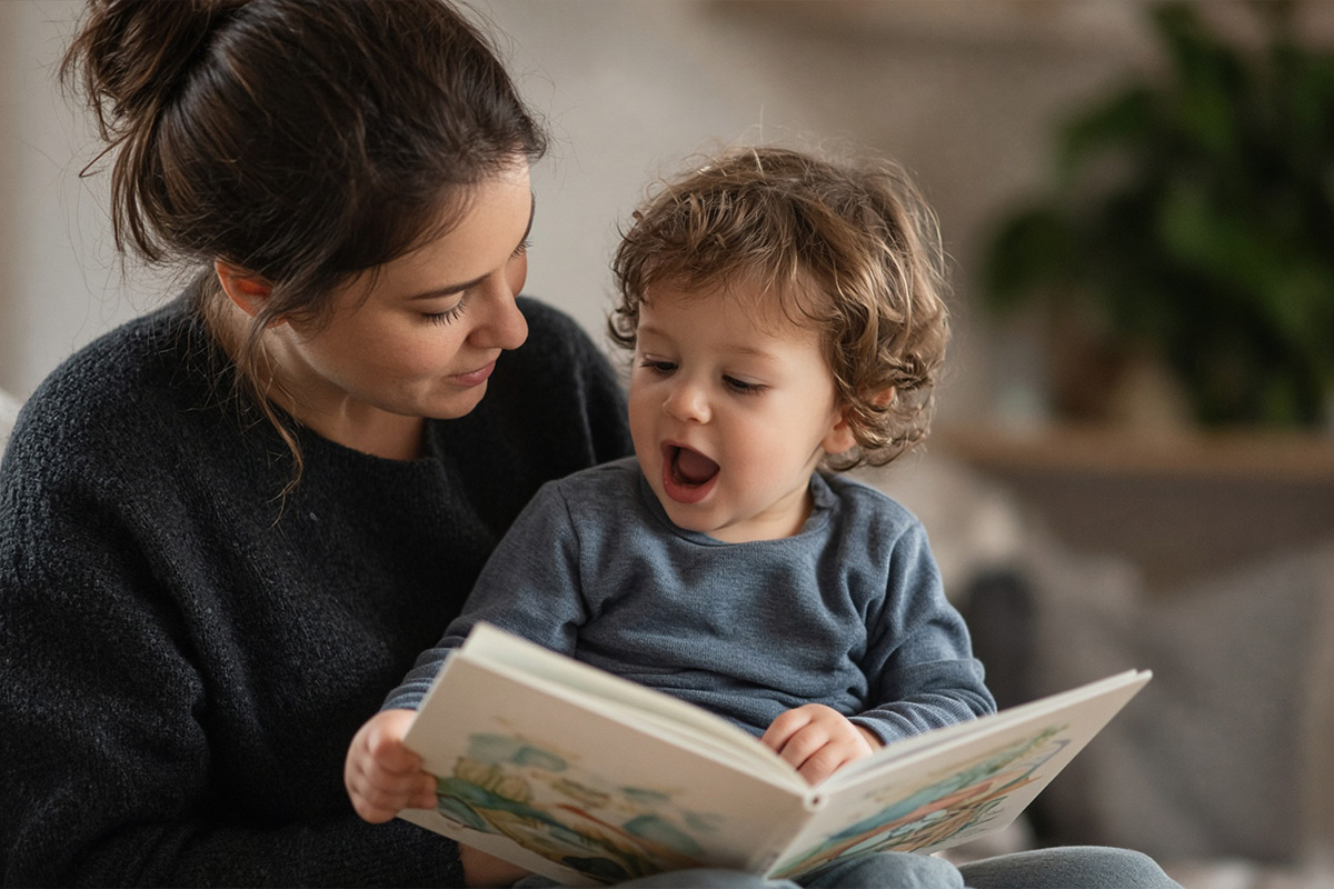 Adult and toddler looking at a book, child vocalizing